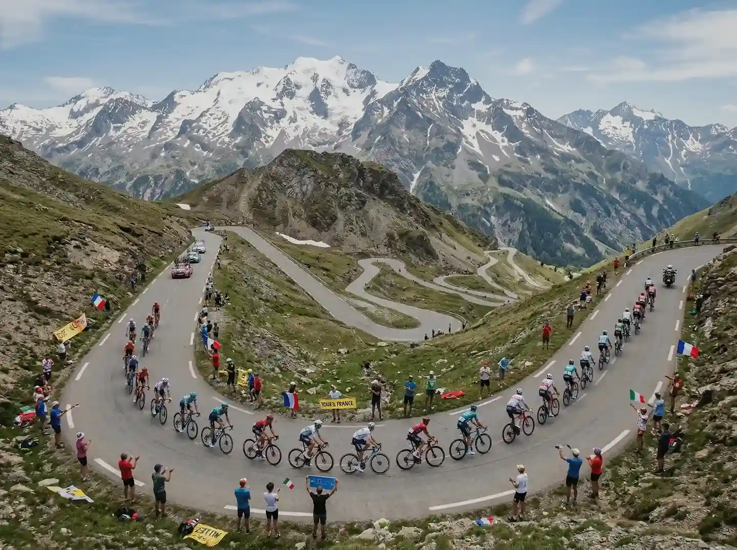 Peloton du Tour de France gravissant un col alpin spectaculaire vu du ciel avec les lacets de montagne